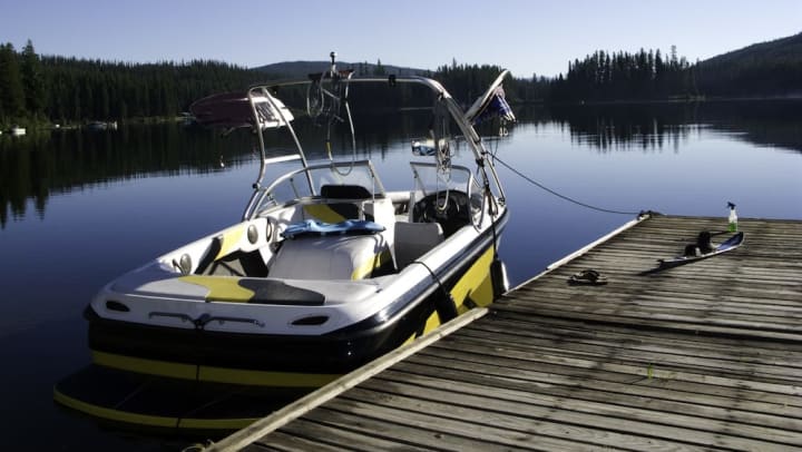 A boat tethered to a dock out at a lake