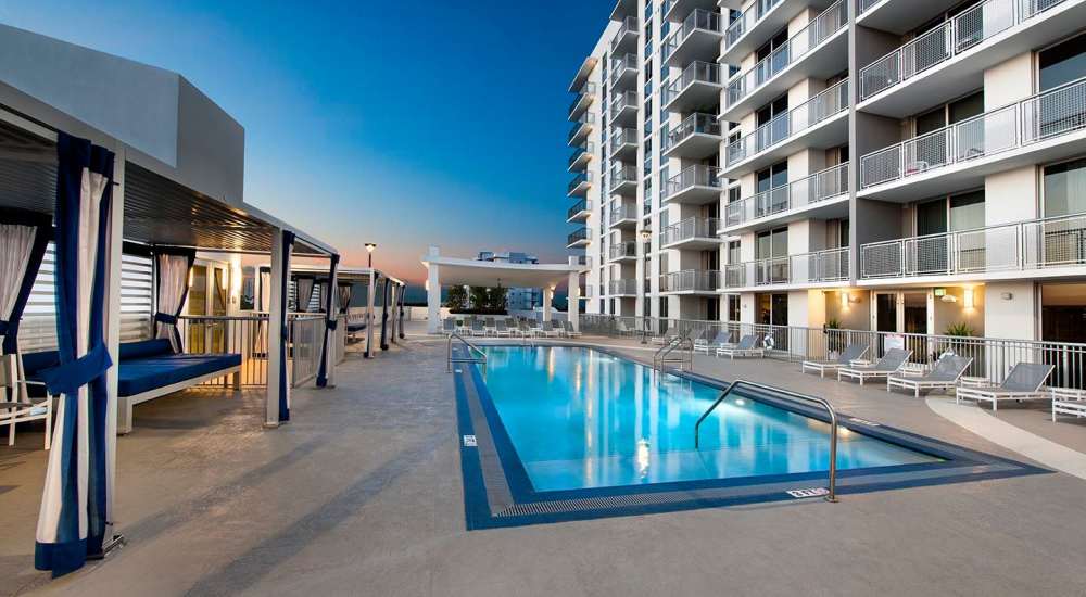 Swimming pool with gazebos and chaise lounge seating at Grove Station Tower in Miami, Florida