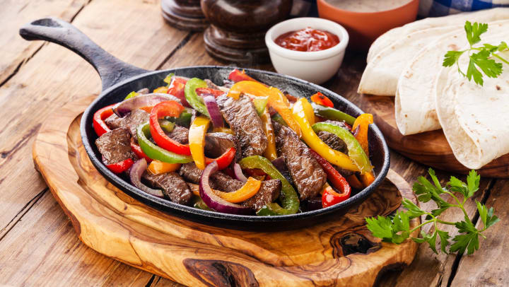 close up of steak fajitas with colorful bell peppers in a cast iron pan | best fajitas around Irving
