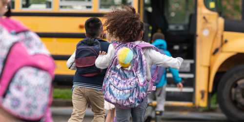 Resident children running joyfully towards their school bus near Creekside at Alyeska in Girdwood, Alaska