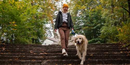 Resident taking her dog for a walk through a verdant park near Comanche Hills in La Mesa, California