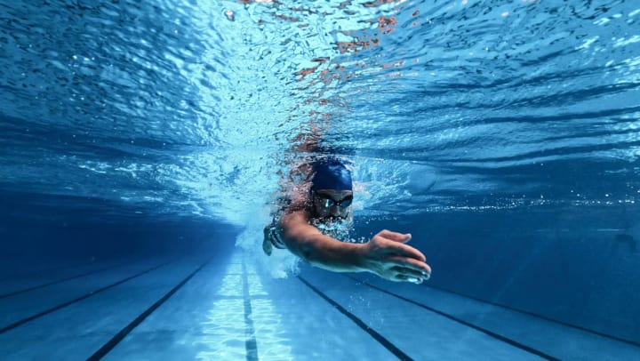 man practicing beginner swimming stroke in a large pool