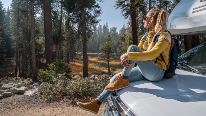 Woman sitting on the hood of a recreational vehicle
