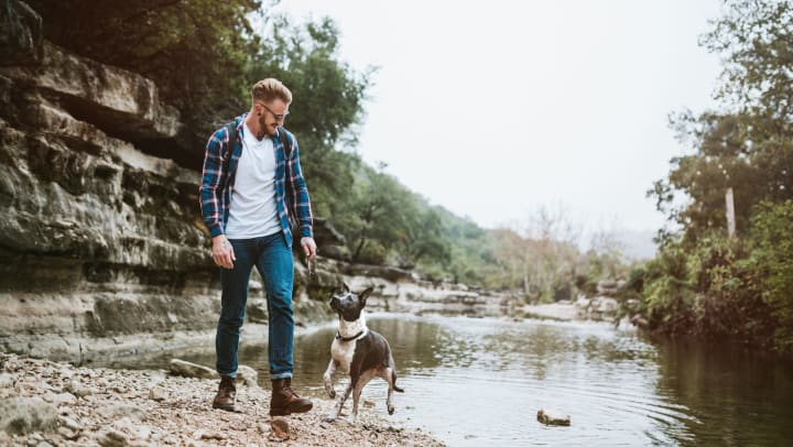 Man walking with his dog along a river near Austin, Texas.