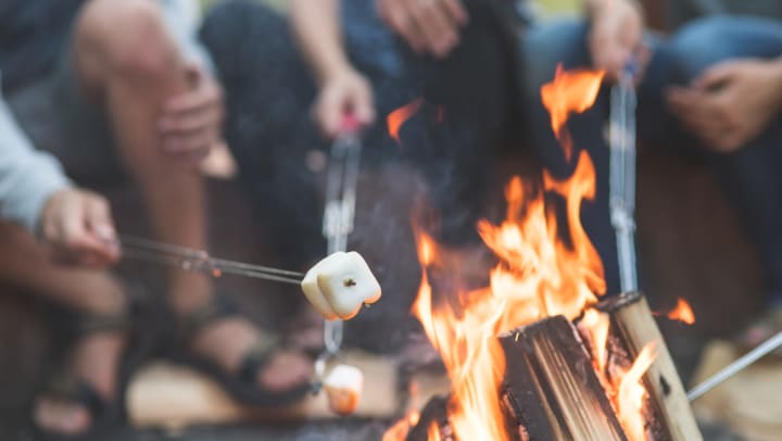 People sitting around a fire, roasting s’mores