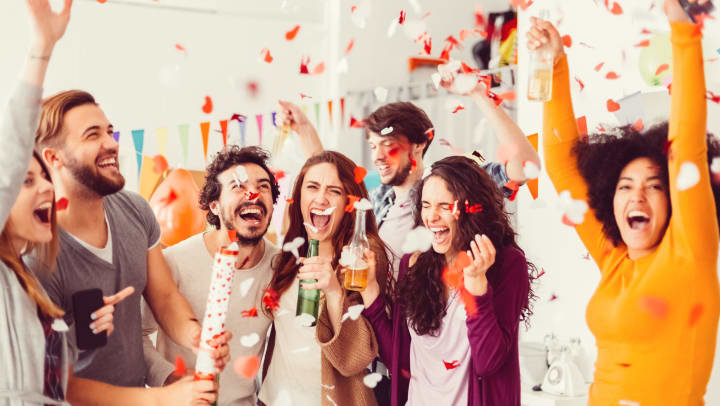 Group of friends celebrating with drinks and confetti.