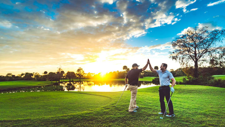 Two male golfers high five on a golf course | golf courses around Raeford