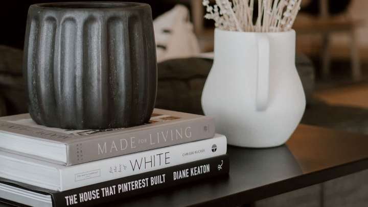 Decorative vases displayed on a stack of design and home décor books on a coffee table, showcasing a modern apartment living aesthetic.