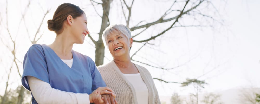 Resident and caretaker taking a walk outdoors together at Burton Health Care Center in Burton, Ohio