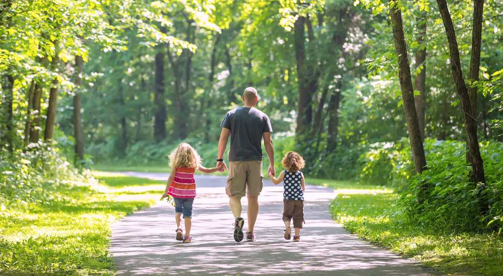 Resident with his two kids walking in a park near Briar Forest Lofts in Houston, Texas