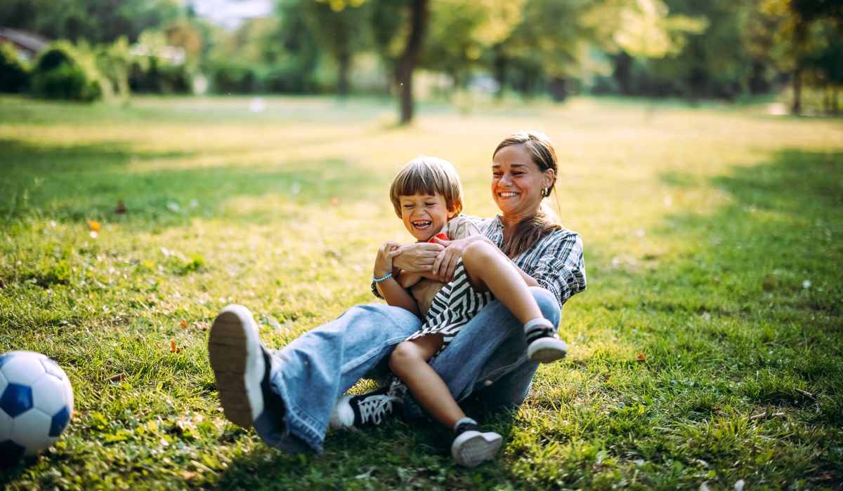Mother and her kid playing football in a park near Whispering Pines Ranch in The Woodlands, Texas