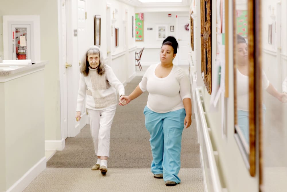 Staff member walking a resident down a hallway at Providence Assisted Living in Clarksville, Arkansas. 