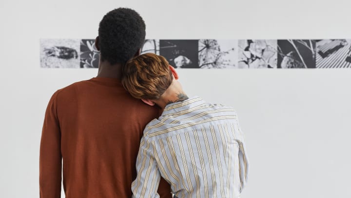 Couple embracing while looking at paintings at modern art gallery exhibition