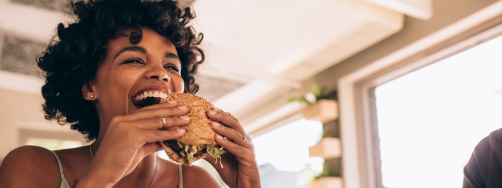 A woman takes a bite of a burger near M2 Apartments in Denver, Colorado