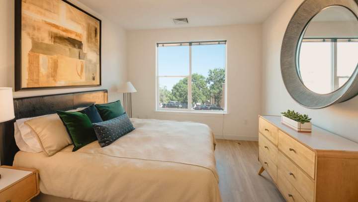 Bright bedroom with large window and wood-style flooring at {{location_name}} in {{location_city}}, {{location_state_name}}