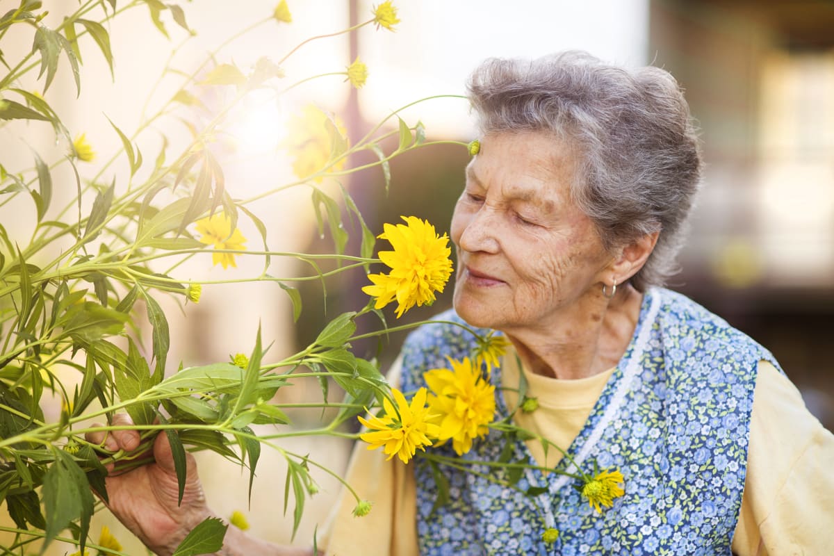 A woman smelling flowers at Harbor Cove Memory Care in Hilton Head Island, South Carolina