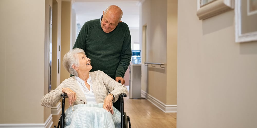 Elderly man pushing wife in wheelchair at Vista Prairie at Brentwood in Rice Lake, Wisconsin