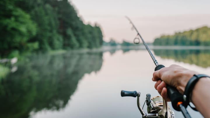 A male fisherman threw a spinning rod into a lake or river on a