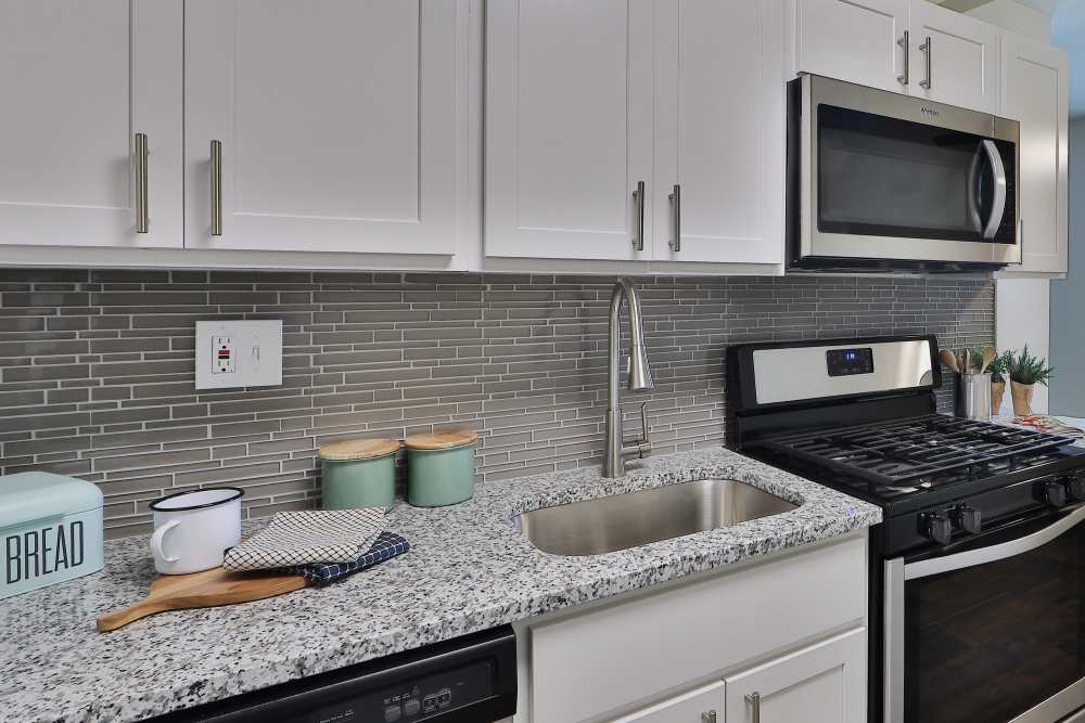 Kitchen with white cabinets, granite countertops, and stainless steel appliances at Cranbury Crossing Apartment Homes in East Brunswick, New Jersey