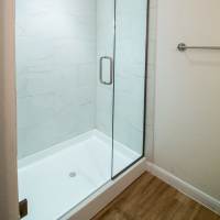 Shower with glass door and wood-style flooring at Sutton in Austin, Texas
