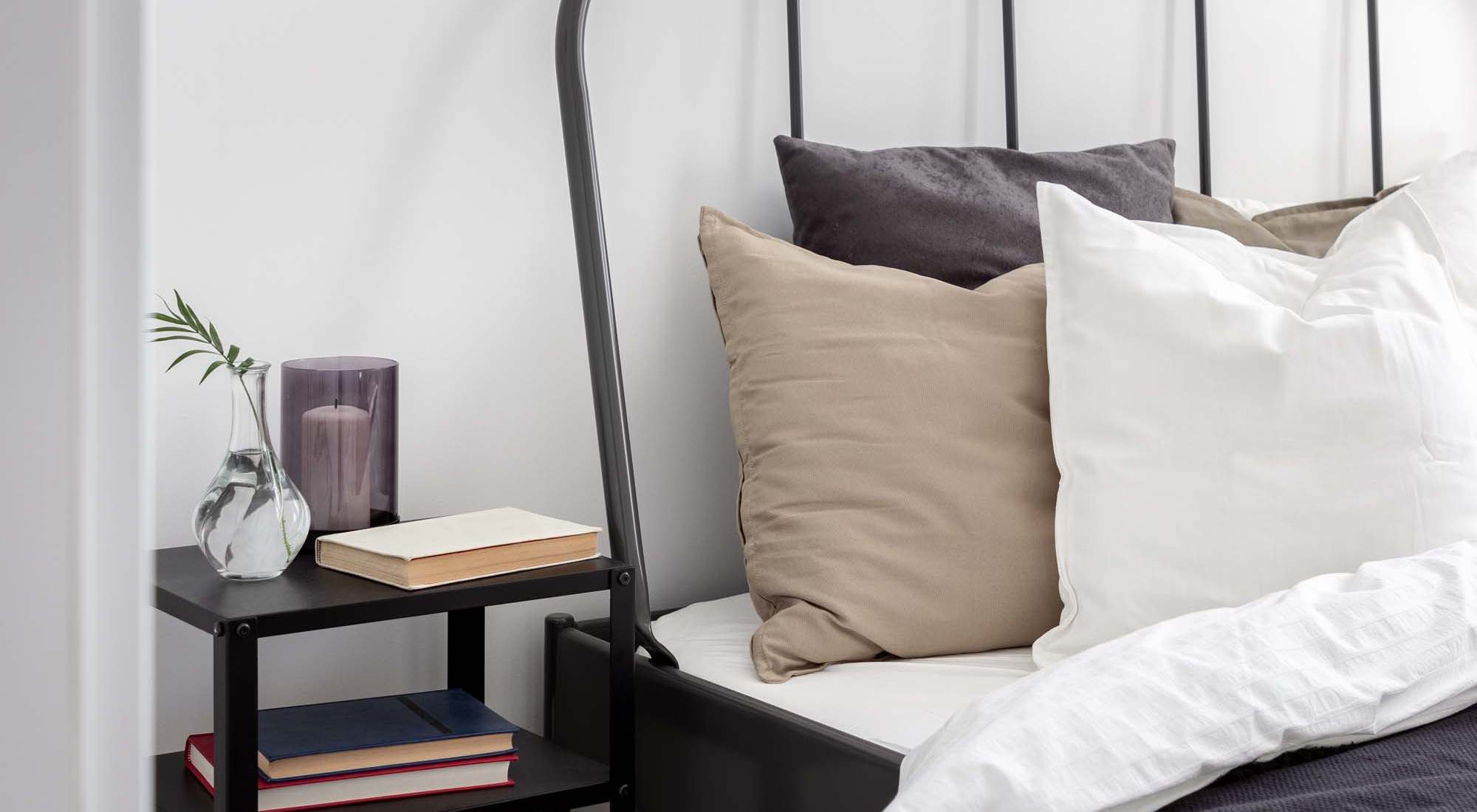 A black iron bed frame adorned with white pillows, located at Granite Creek in Rocklin, California.