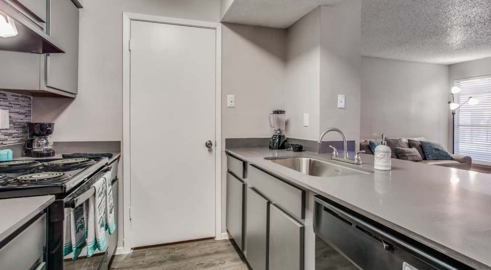 Modern apartment kitchen with gray cabinetry at Athena Apartments in Benbrook, Texas