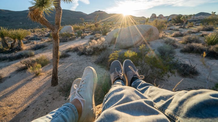 Couple relaxing on top of boulder rock at sunrise