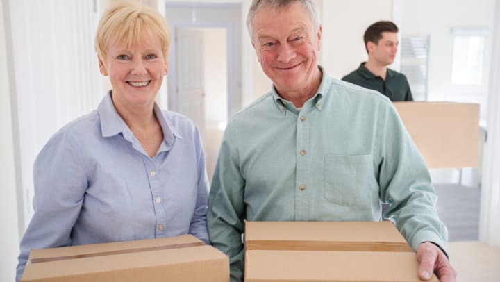 happy senior adult couple carrying moving boxes