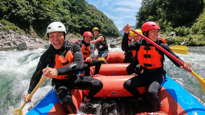 a group of six in a raft, paddling through rapids | Whitewater Center