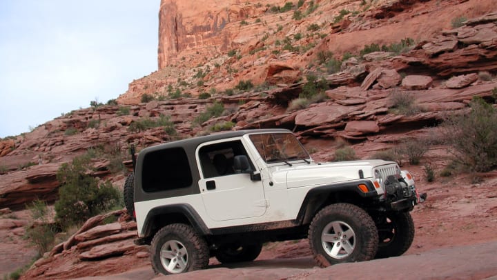A white Jeep driving through the desert canyons.