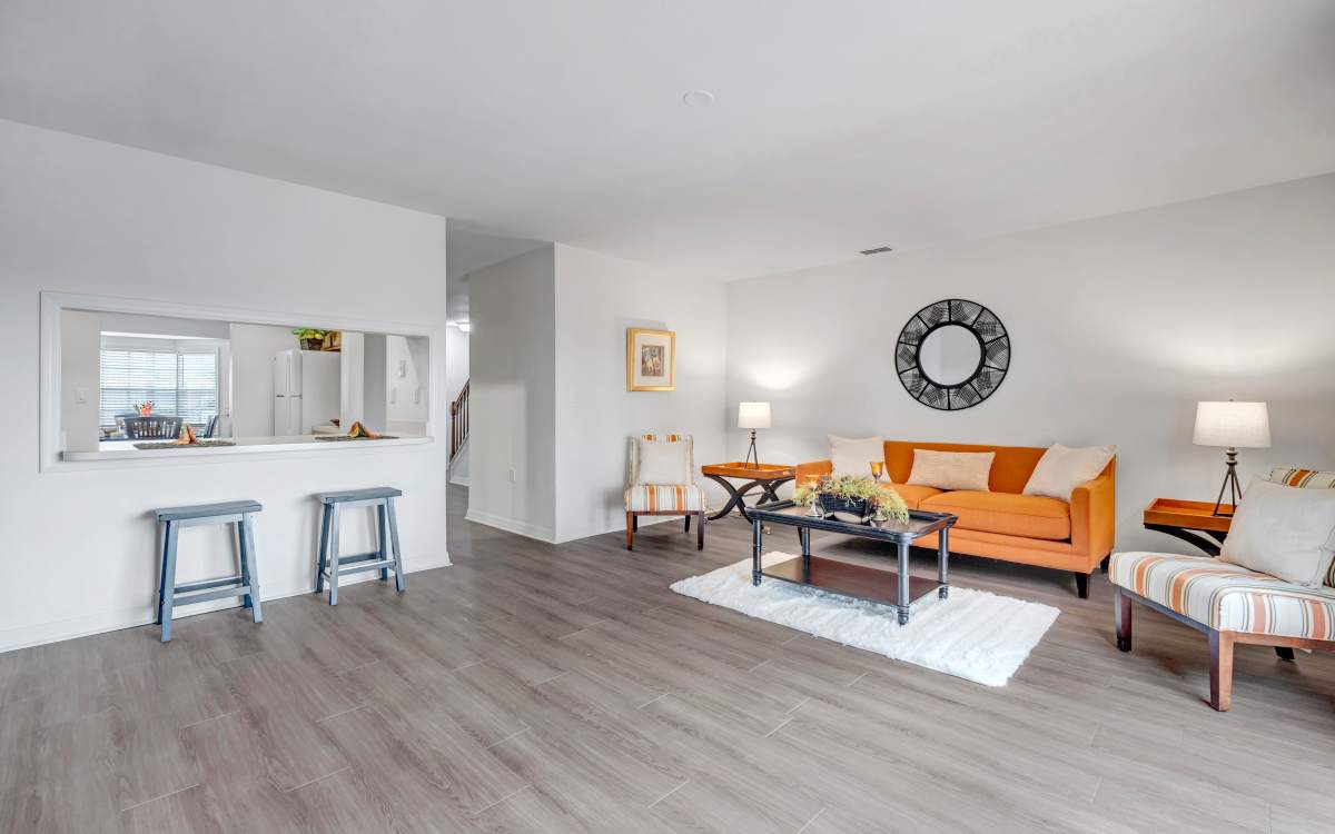 Spacious living room with wood-style flooring, modern furniture, and open layout kitchen view at Carlton Arms Of Winter Haven in Winter Haven, Florida