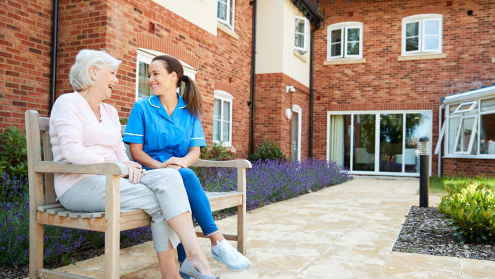 Woman and nurse talking outside on bench