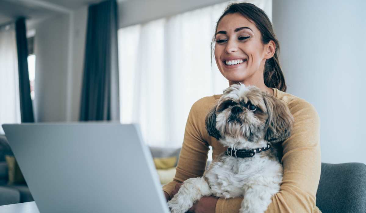 Woman working in a laptop while holding a dog in her hands at Autumn Oaks Apartments in Suisun City, California