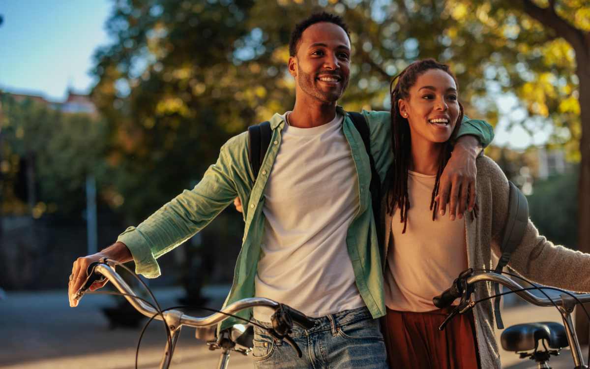 A young smiling couple joyfully standing beside their bicycles in a sunny outdoor near Pine View in La Pine, Oregon