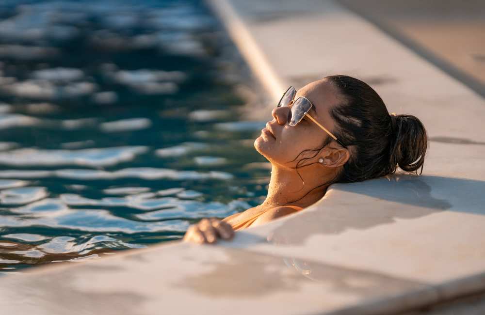 A woman relaxing in the swimming pool at Pinecrest Apartments in Fallbrook, California