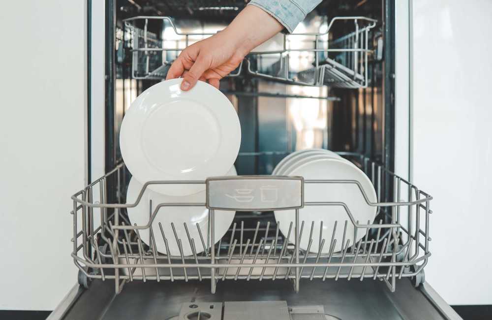 Resident taking out the plates from dish washer at Athena Garden Apartments in Athens, Texas