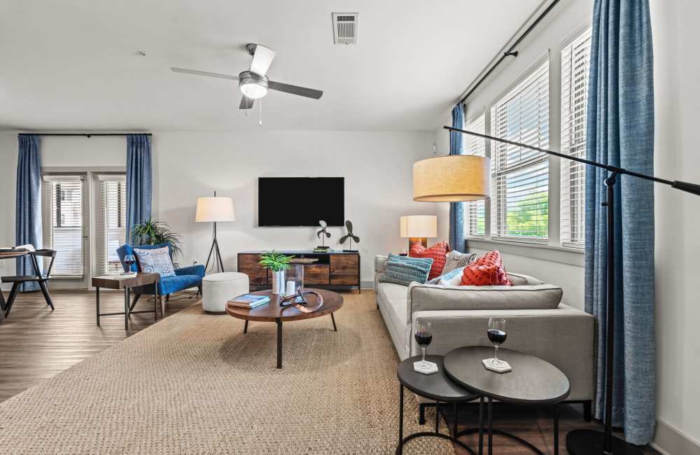 Spacious living room with couch, coffee table, ceiling fan and large window at Watersound Origins Crossings in Inlet Beach, Florida