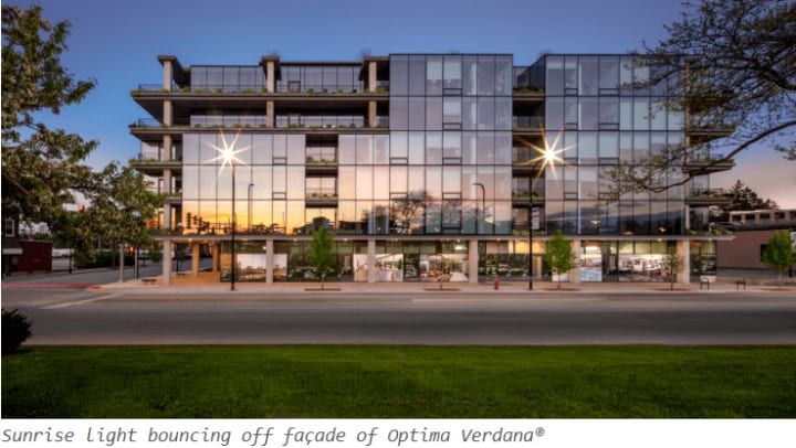 Modern apartment building exterior illuminated at dusk, showcasing sleek lines and large windows against a twilight sky.