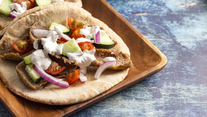 Two gyros with vegetables and white sauce on a wooden table | Greek restaurants in Meridian