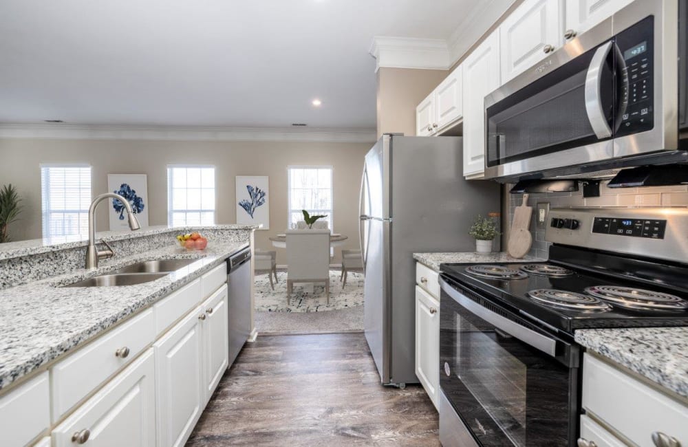 Kitchen with modern white cabinets, stainless appliances, and granite countertops at Christopher Wren Apartments & Townhomes in Wexford, Pennsylvania