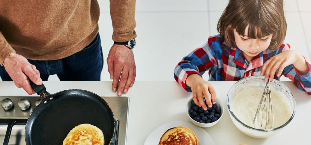 Man and his child fixing up pancakes in their kitchen at Sandpiper Apartments in Seatac, Washington