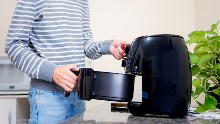 person taking food out of an air fryer | air fryer snacks 