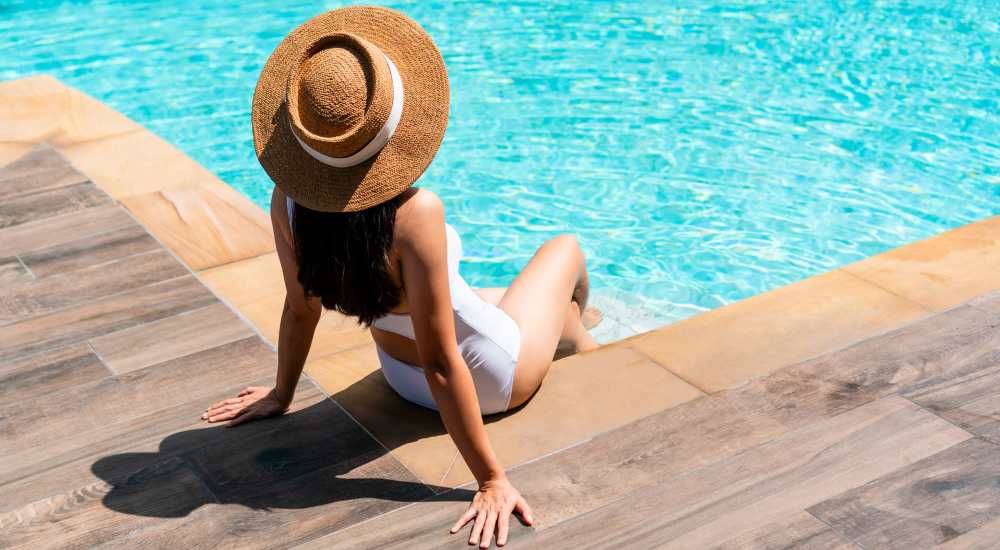 Resident sitting on the edge of sparkling water swimming pool at Arbors at the Reservoir in Ridgeland, Mississippi