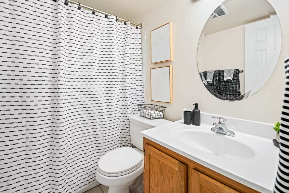 Bathroom with a toilet, mirror and wooden storage units at Windsor Court and Tower in Silver Spring, Maryland
