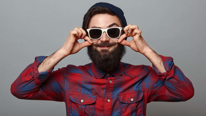 Man smiling with sunglasses and holding his mustache at the ends