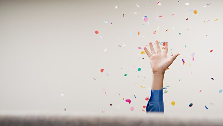 A person’s hand throwing confetti in the air