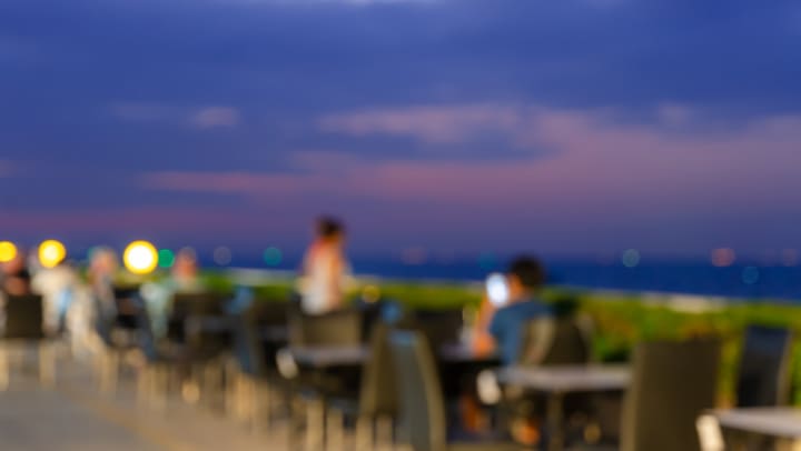 Blurred dining table restaurant poolside at rooftop with beautiful sea view at twilight scene