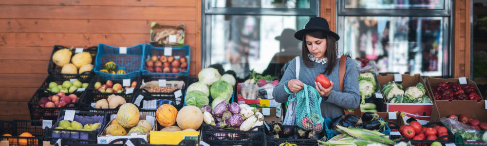A woman looking at produce in front of a store near Cobbs Creek Apartment Homes in Decatur, Georgia