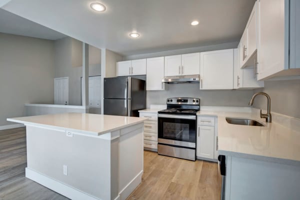 A modern kitchen with shiny stainless steel appliances and sleek white cabinets at Chandlers Bay Apartments in Kent, Washington