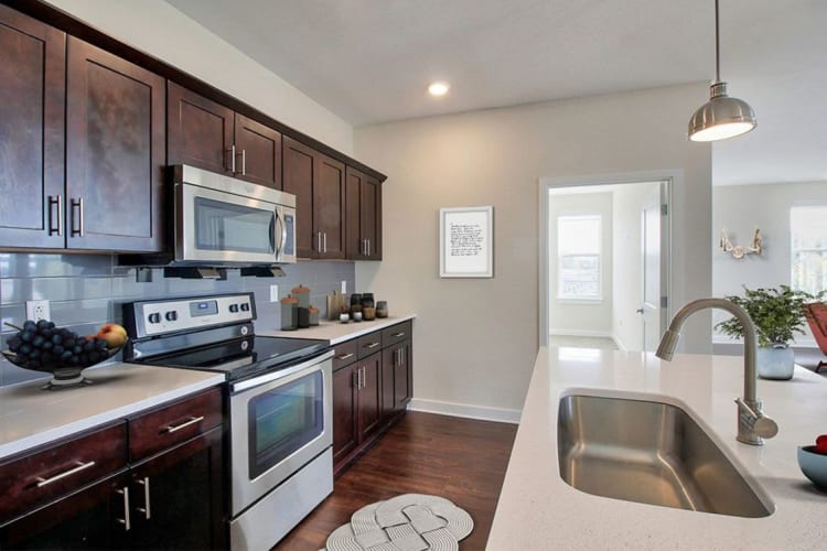 Well-equipped kitchen with quartz countertops in a model home at Pinnacle North Apartments in Canandaigua, New York